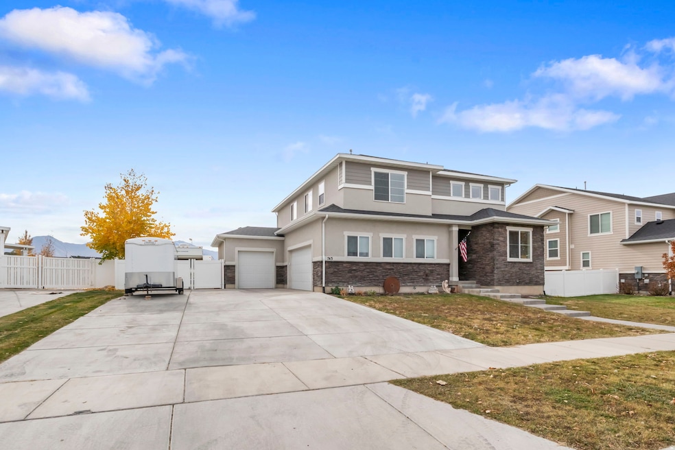 Prairie-style home with stone siding, stucco siding, driveway, and a gate