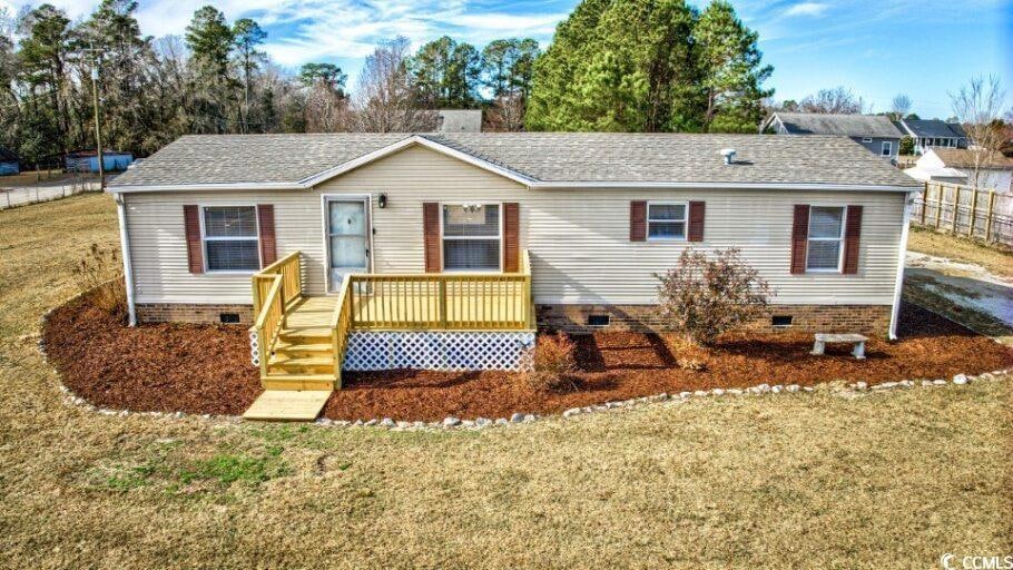 Single story home featuring crawl space, roof with shingles, a front yard, and a wooden deck