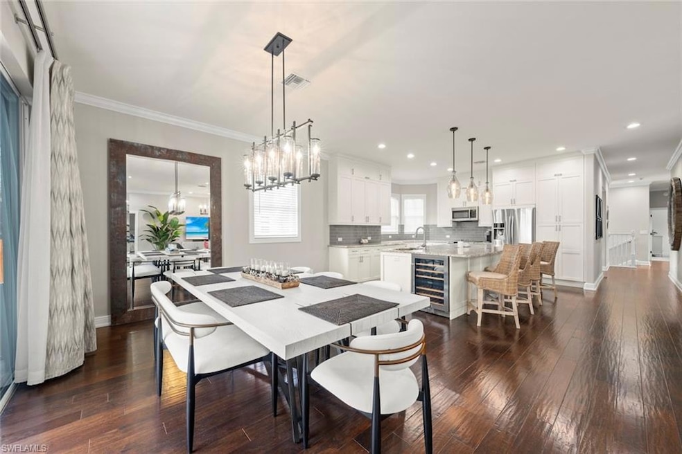 Dining room featuring dark wood-style flooring, modern lighting and crown molding as well as Kitchen island Quartz counter tops and built in beverage cooler.