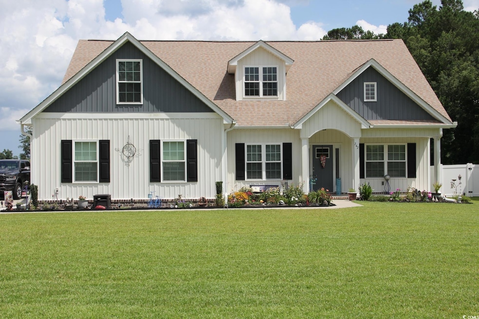 View of front of property with roof with shingles, a front yard, and board and batten siding
