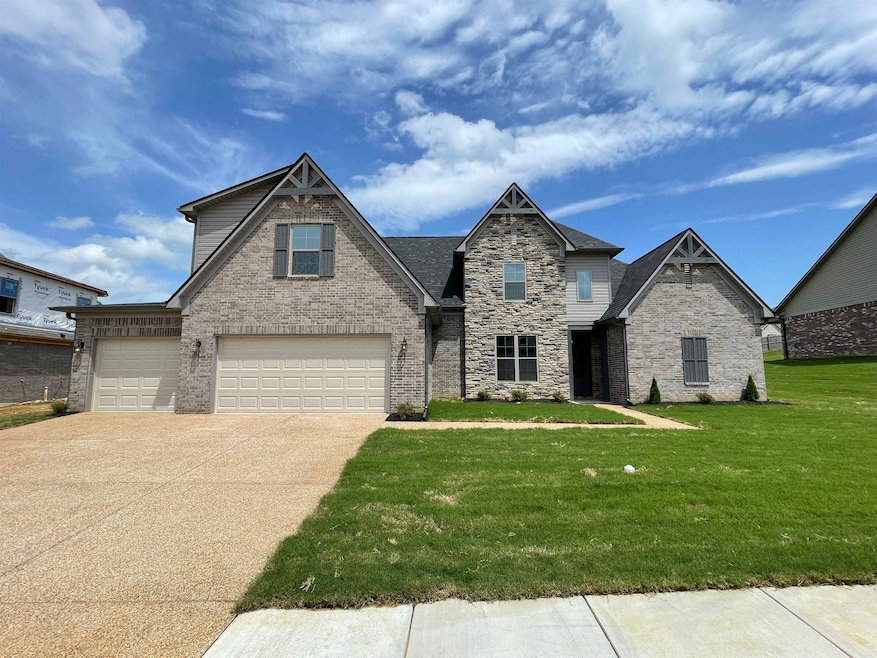 View of front facade featuring a front yard, driveway, stone siding, a garage, and brick siding