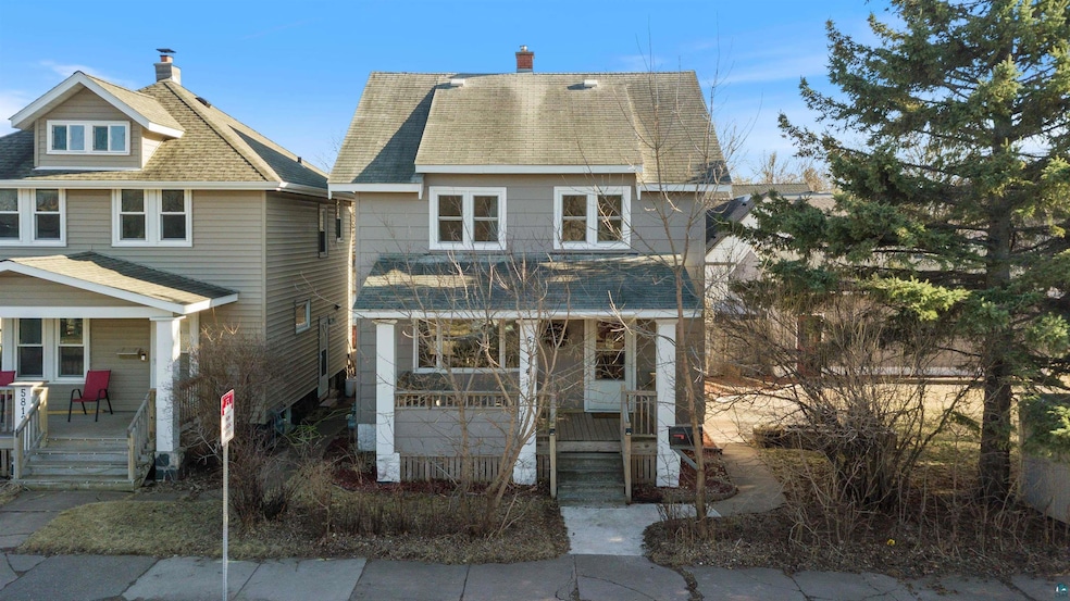 View of front of property featuring a chimney, a shingled roof, and covered porch