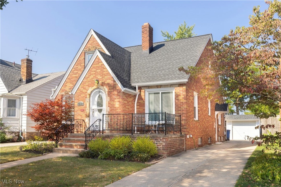View of front of property featuring a garage, a front yard, and an outbuilding