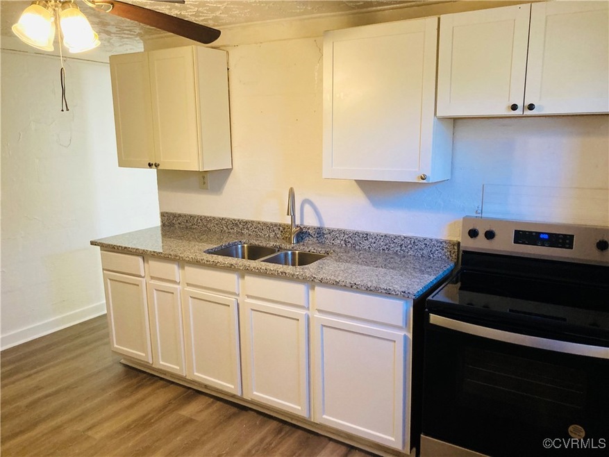 Kitchen with electric stove, a sink, and white cab