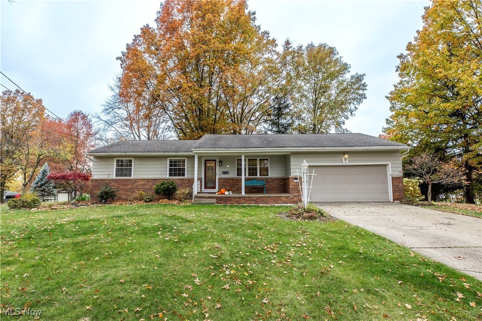 Ranch-style home featuring a porch, brick siding, a front yard, concrete driveway, and a garage