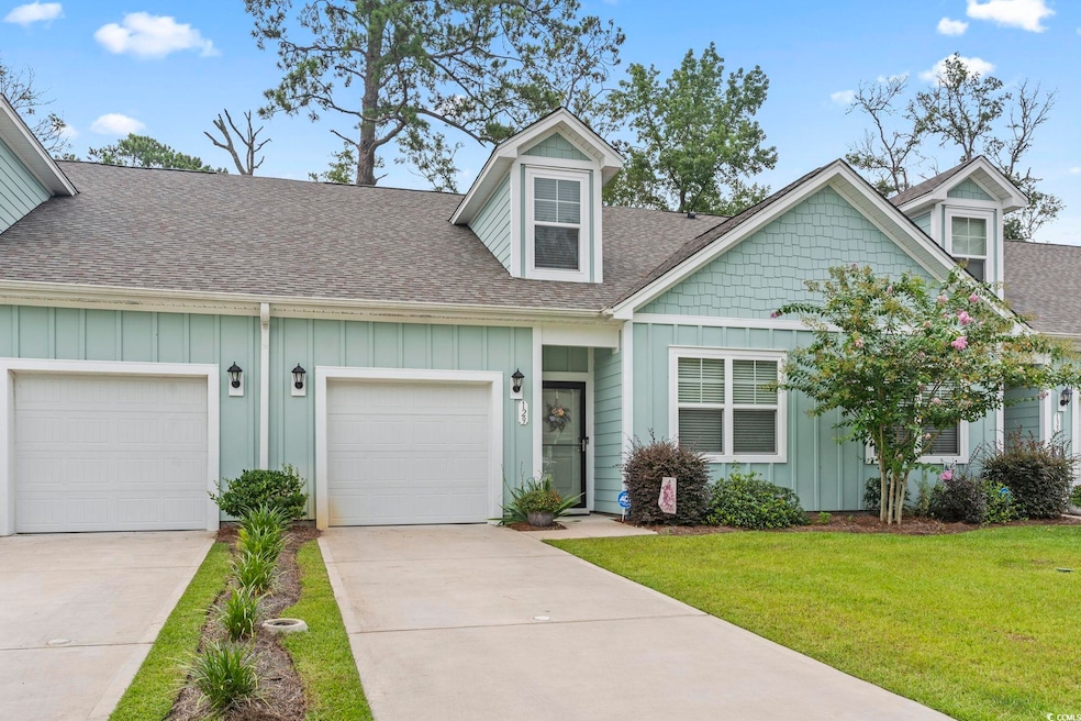 View of front facade with board and batten siding, driveway, a shingled roof, and a front lawn