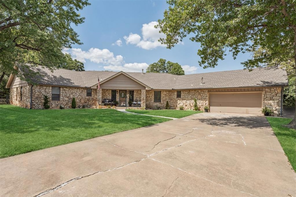 Ranch-style home featuring stone siding, roof with shingles, and a front lawn