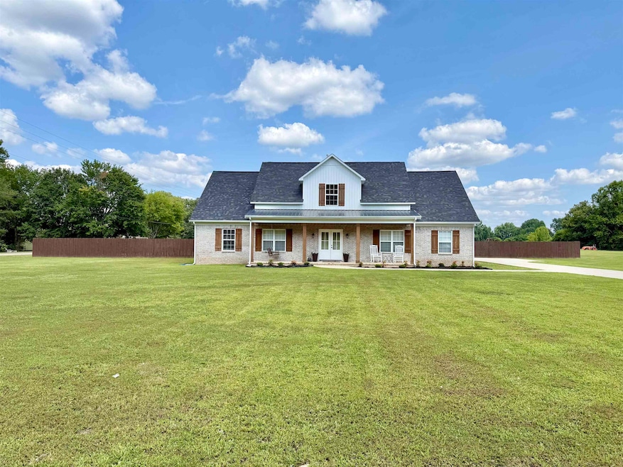 View of front of property featuring a shingled roof, brick siding, and covered porch