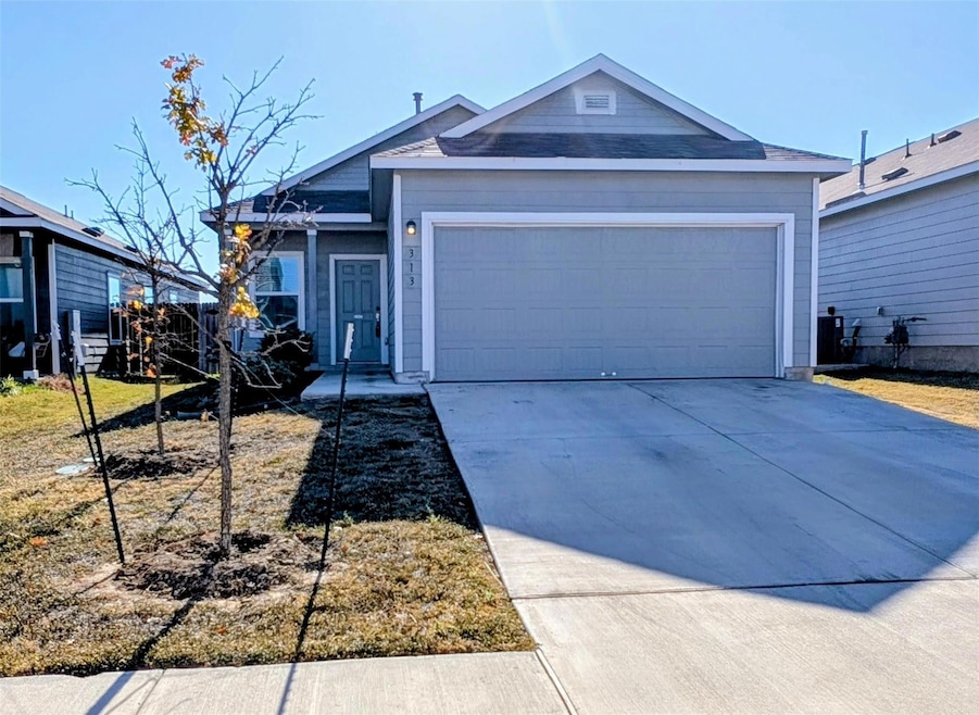 Ranch-style house featuring concrete driveway, an attached garage, and roof with shingles