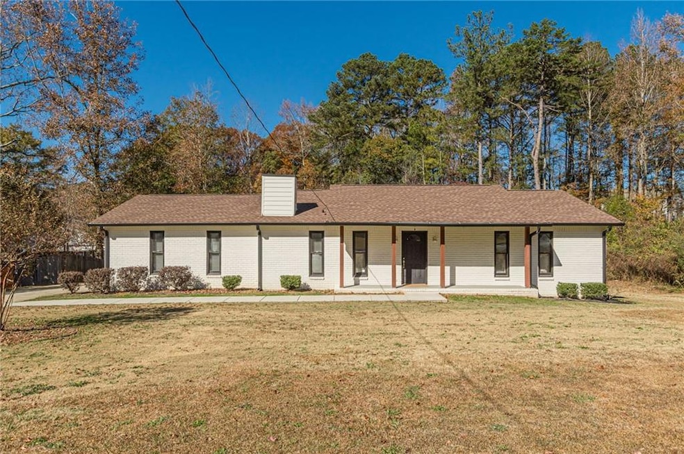 Ranch-style home with covered porch, a front yard, a chimney, and roof with shingles
