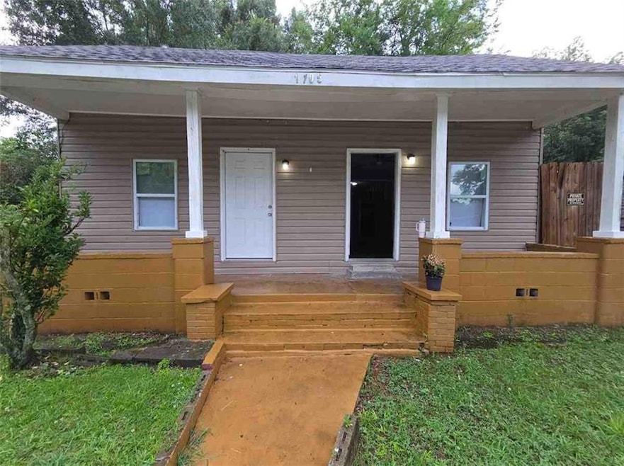 View of front of home with covered porch, crawl space, and roof with shingles