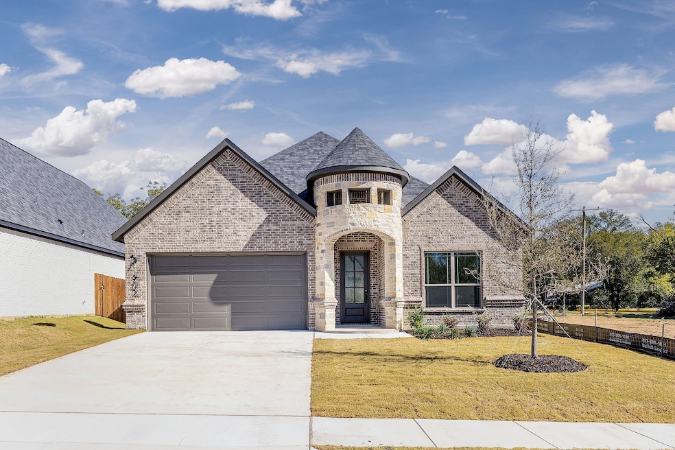 French country home with brick siding, stone siding, driveway, a garage, and a high end roof