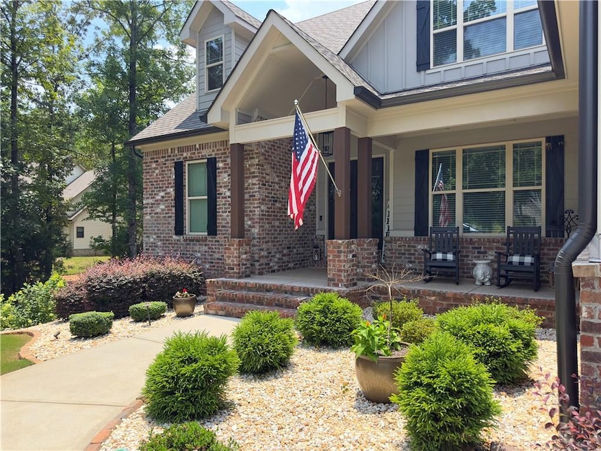 View of exterior entry with covered porch, brick siding, roof with shingles, and board and batten siding