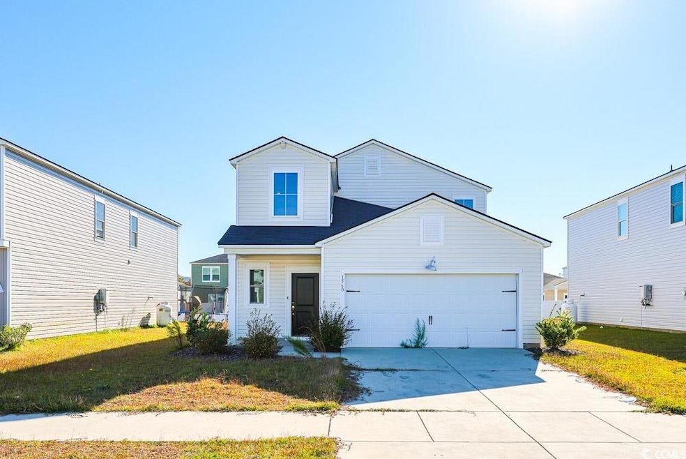 Traditional-style house with a front lawn, driveway, and an attached garage