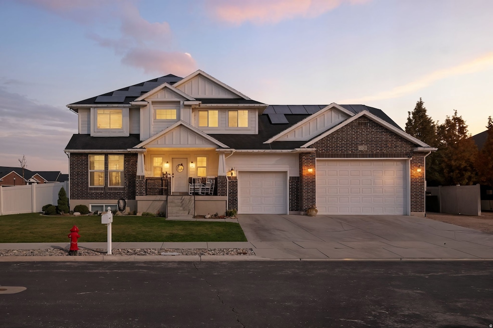 Craftsman-style home with board and batten siding, covered porch, driveway, brick siding, and roof mounted solar panels