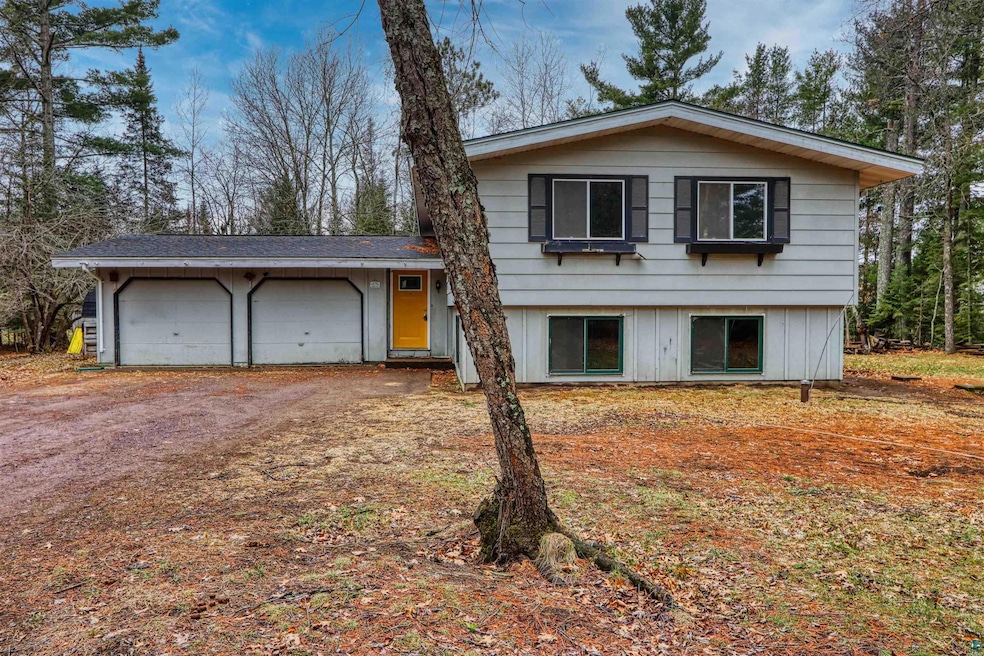 Tri-level home featuring dirt driveway and a garag