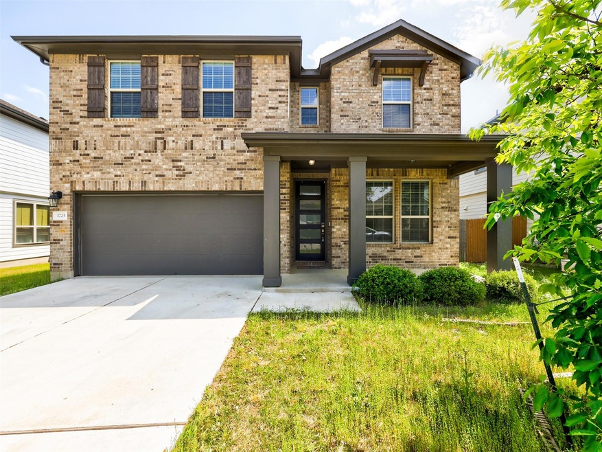 View of front facade with brick siding, an attached garage, a porch, and driveway