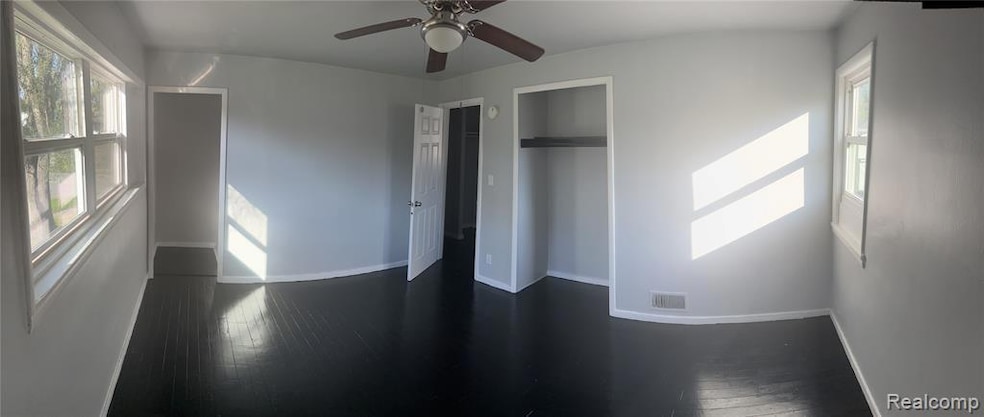 Unfurnished bedroom featuring dark wood finished floors, ceiling fan, and a closet