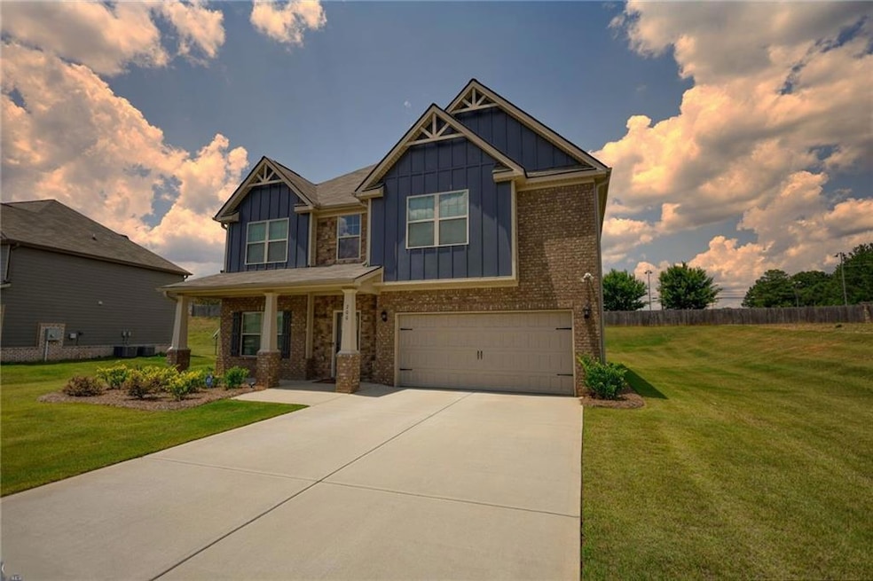 Craftsman-style home featuring board and batten siding, a garage, concrete driveway, brick siding, and covered porch