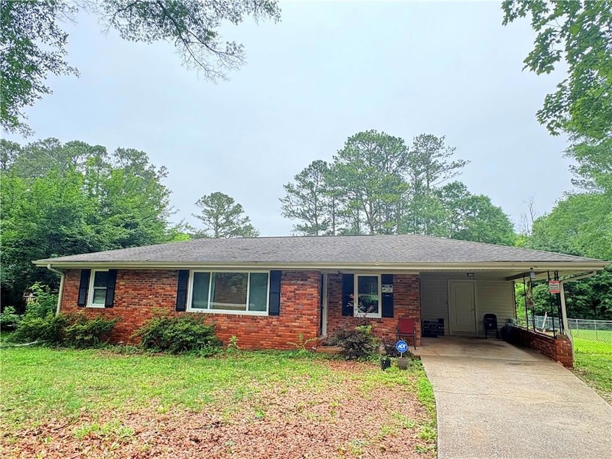 Single story home with driveway, an attached carport, and brick siding