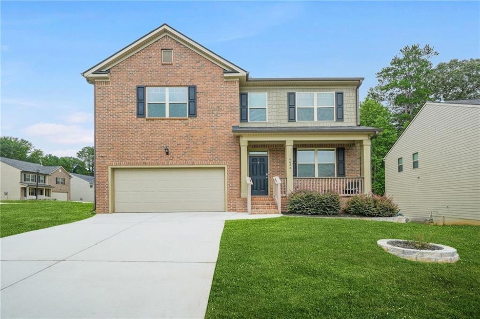 View of front of property featuring a porch, concrete driveway, a front yard, and an attached garage