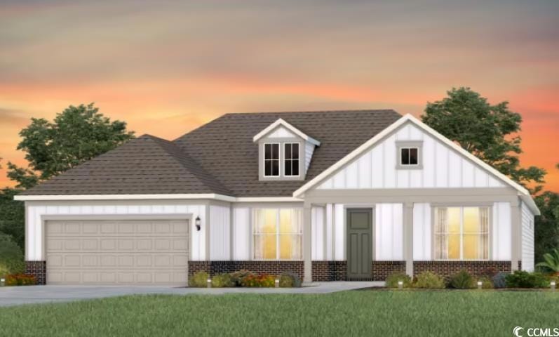 View of front of home featuring brick siding, board and batten siding, an attached garage, and a yard