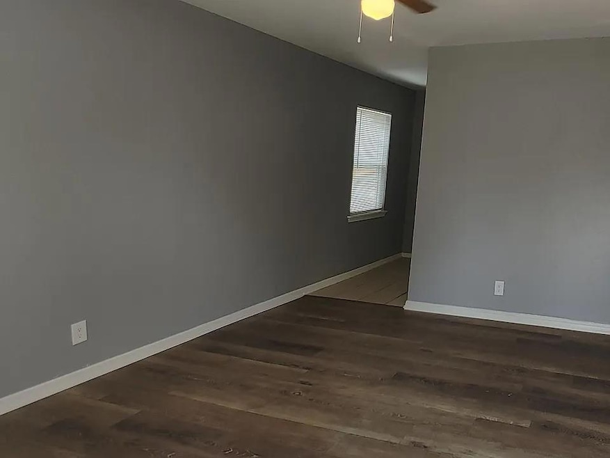 Spare room featuring ceiling fan and dark wood-type flooring