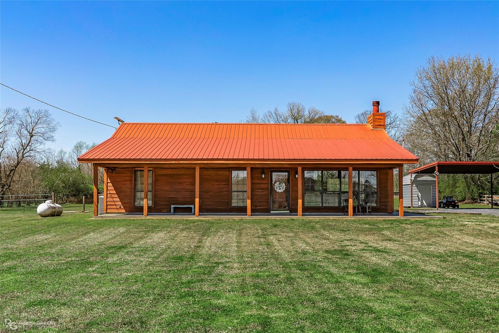 Back of house with a carport, a lawn, an outdoor s
