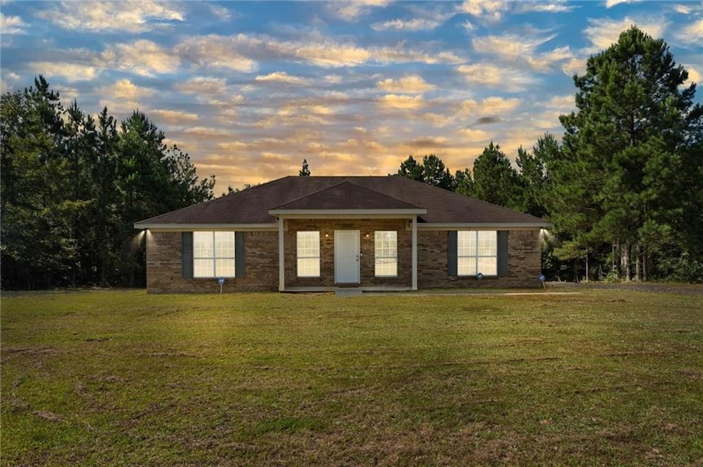 View of front of house featuring a lawn and brick siding