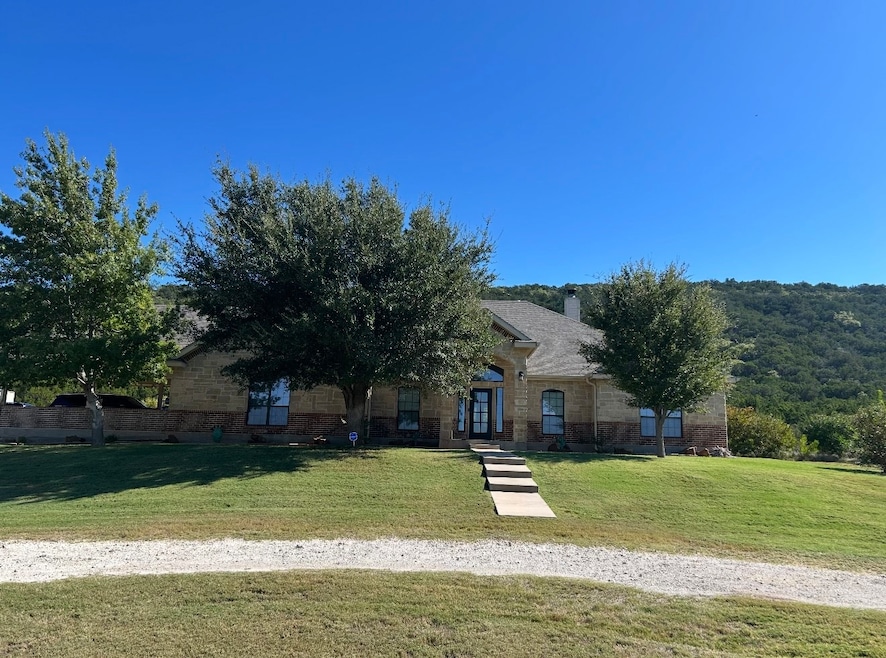 View of property hidden behind natural elements featuring a front yard, a chimney, and brick siding