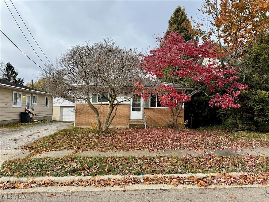 View of front of home with an outbuilding, brick siding, a garage, and driveway