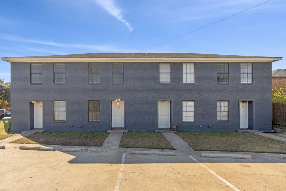 Colonial home with uncovered parking, brick siding, and a front yard