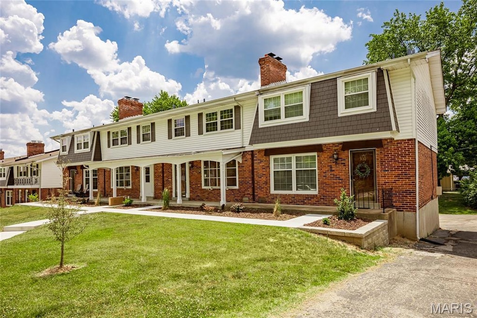 View of front facade with a chimney, brick siding, and a front yard