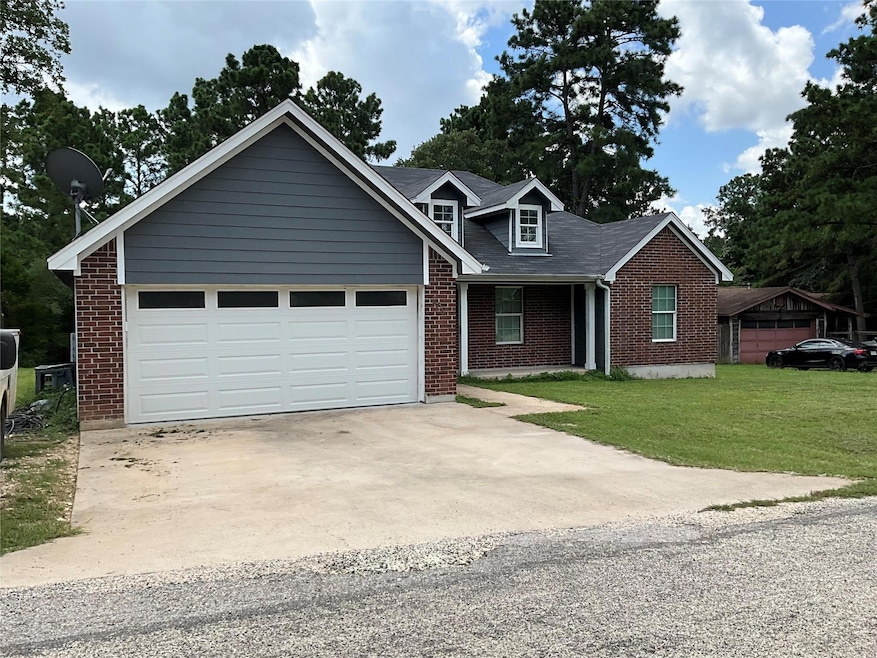 View of front of property featuring driveway, brick siding, a front lawn, covered porch, and a garage
