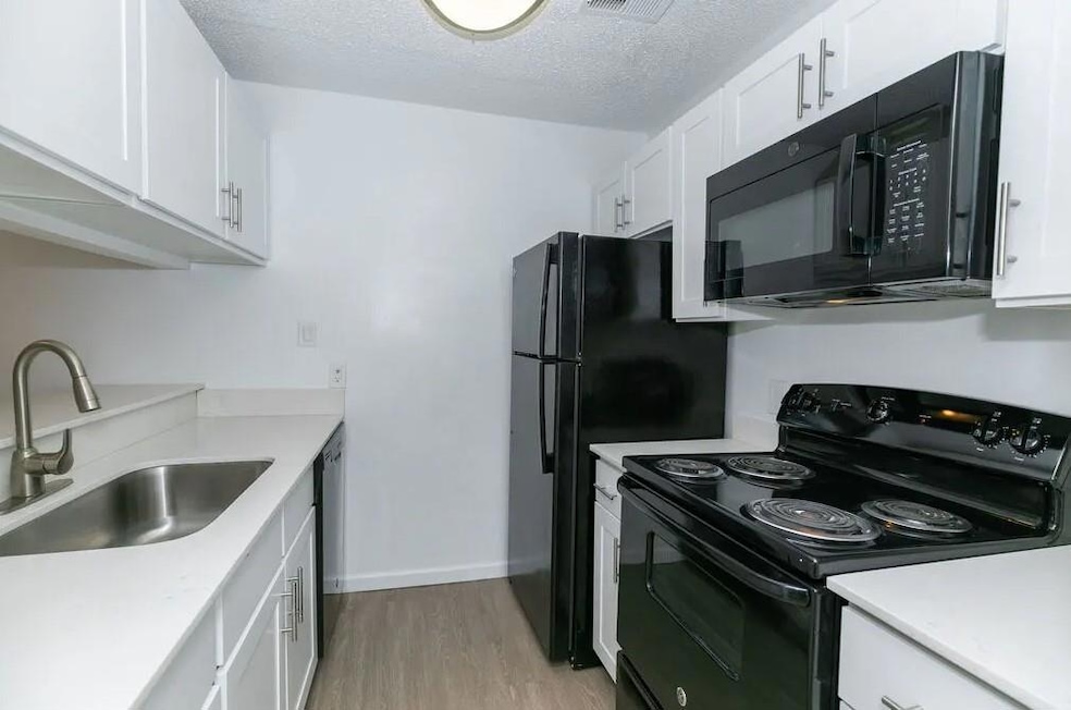 Kitchen with a textured ceiling, white cabinets, s