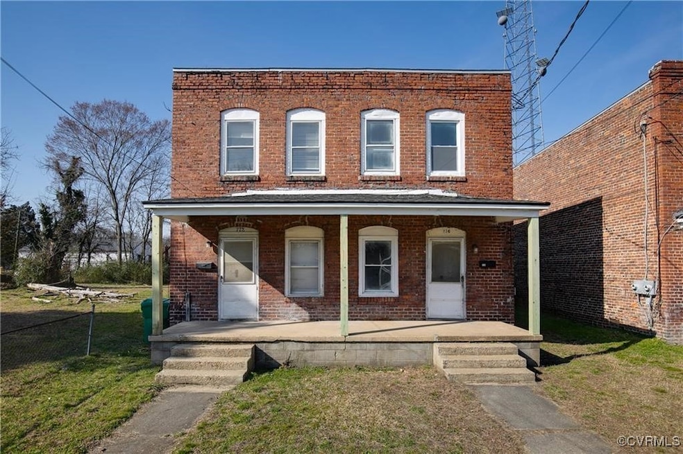 View of property with covered porch, brick siding,