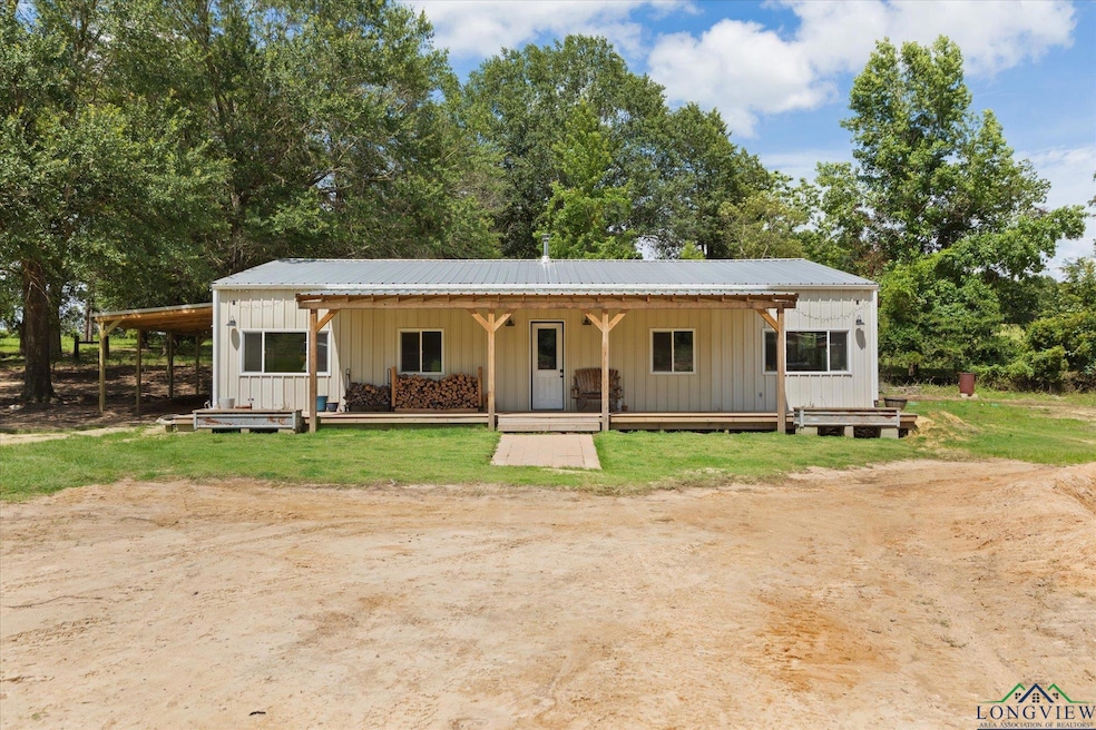 View of front facade featuring board and batten siding, covered porch, a metal roof, and view of scattered trees