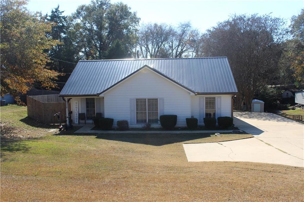 View of front of property featuring a front lawn, a metal roof, a porch, and concrete driveway