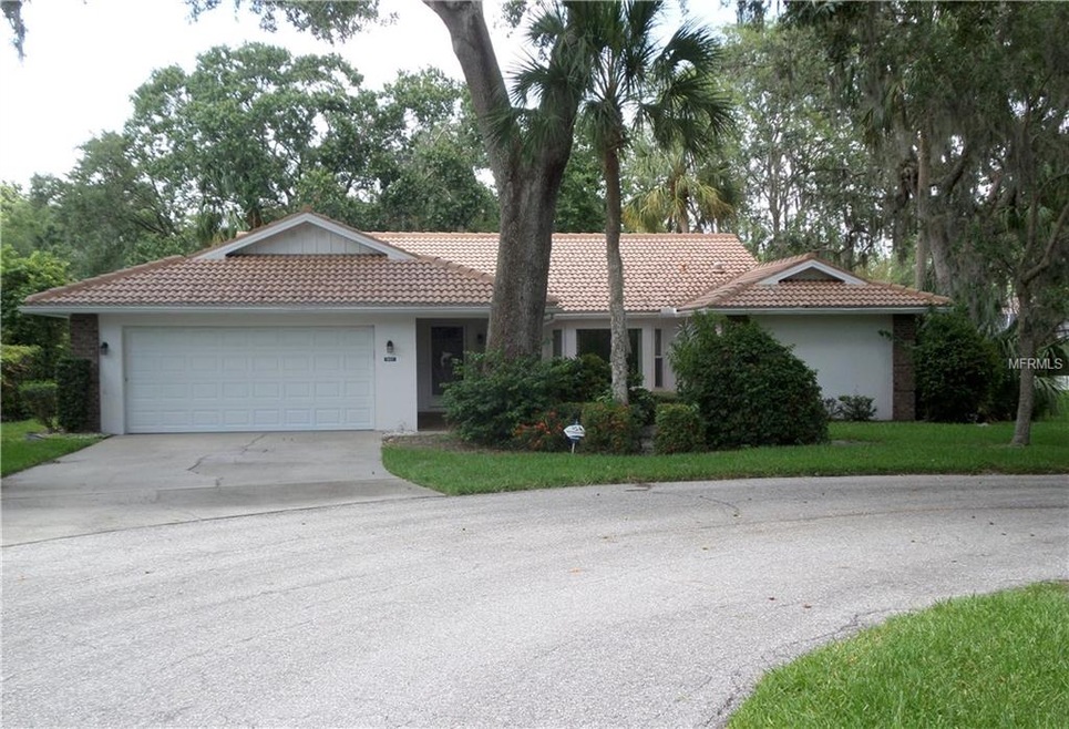 Front view showing wide treed lot, barrel-tile roo