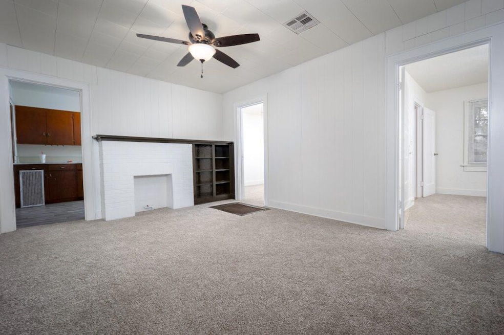 Unfurnished living room with light carpet and a ceiling fan