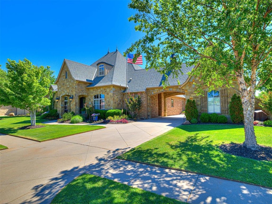 French country home featuring stone siding, driveway, a high end roof, and a front lawn
