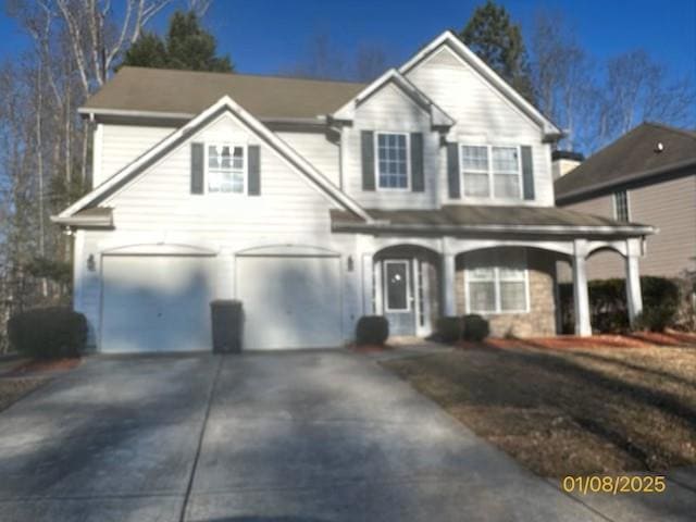 Traditional-style home featuring an attached garage, concrete driveway, and a porch