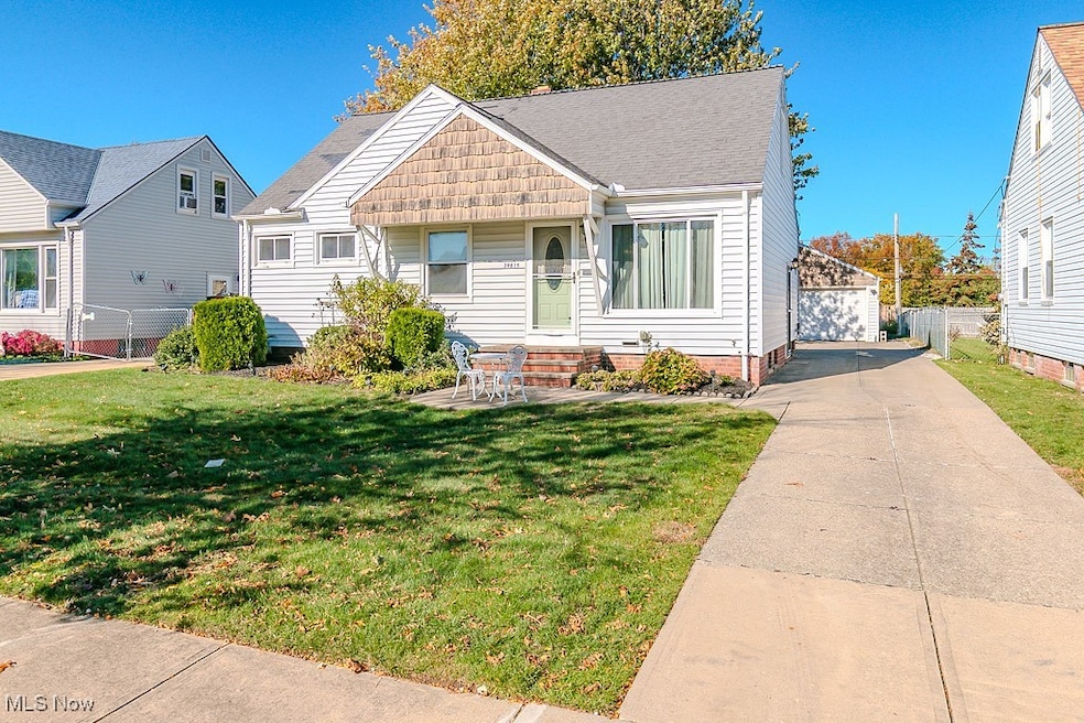 Bungalow featuring a front lawn, roof with shingles, an outbuilding, and a garage