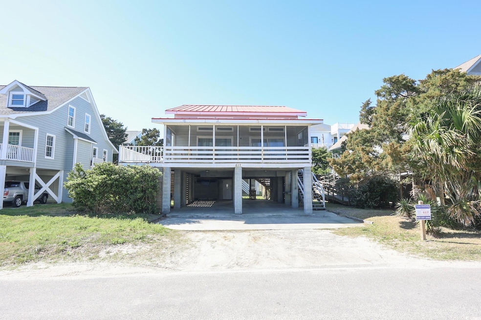 Raised beach house featuring driveway, a standing seam roof, metal roof, a carport, and a sunroom