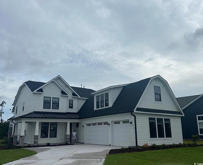 View of front facade featuring a front yard, a gar