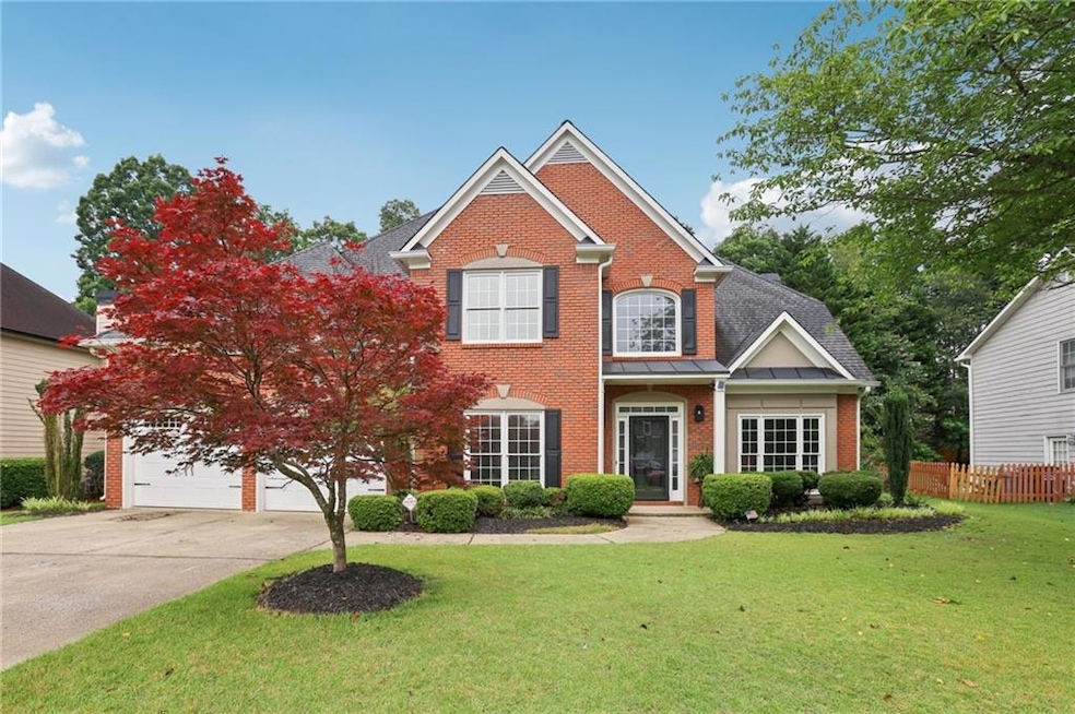 View of front facade with brick siding, driveway, and a garage