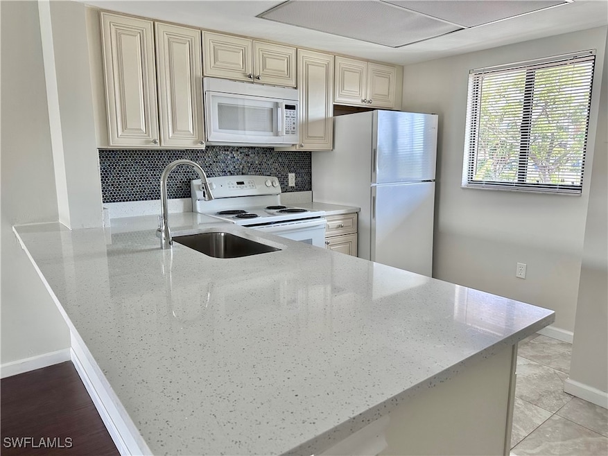 Kitchen with a sink, tasteful backsplash, white ap
