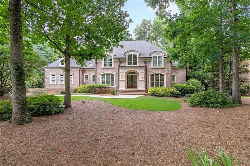 Lush landscaping and 100+ year old oak frame this 