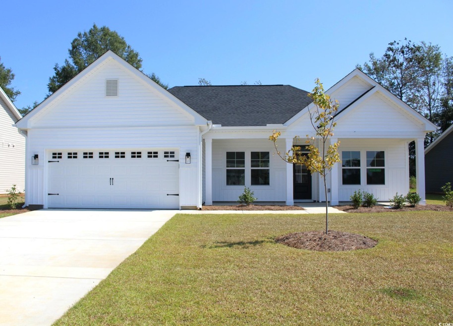 View of front of property featuring a porch, a front lawn, board and batten siding, concrete driveway, and roof with shingles