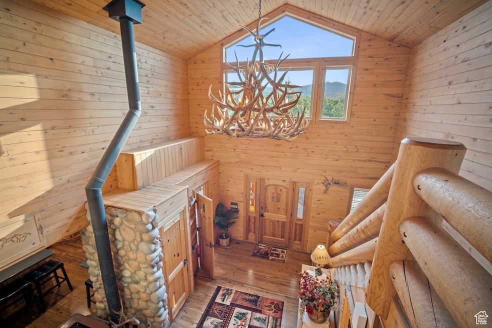 Stairway with a wood stove, wood walls, a chandelier, hardwood / wood-style floors, and wood ceiling